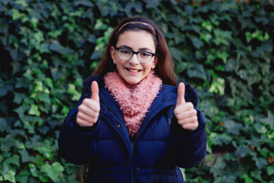 Portrait of smiling young woman standing against plants