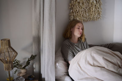 Crying young woman sitting in bed