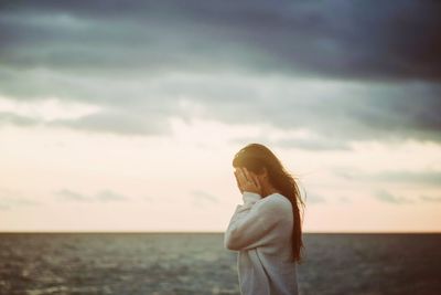 Woman standing by sea against sky