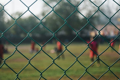 People on soccer field seen through chainlink fence