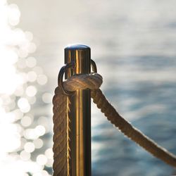 Close-up of rope tied to bollard against sky