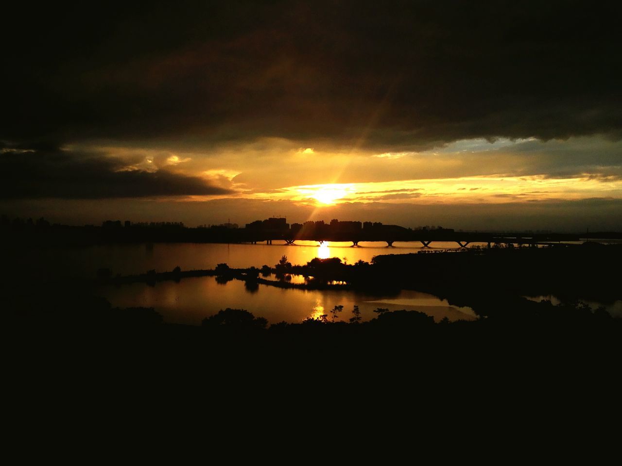 sunset, water, sky, cloud - sky, tranquil scene, scenics, tranquility, reflection, beauty in nature, cloudy, nature, sun, idyllic, cloud, orange color, dramatic sky, outdoors, no people, calm, non-urban scene, weather, moody sky, overcast, majestic, dark, remote