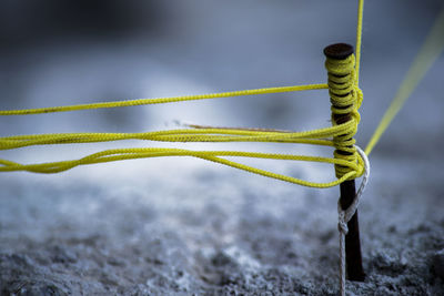 Close-up of yellow rope tied on nail