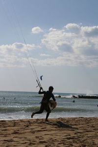 Man fishing at sea shore against sky