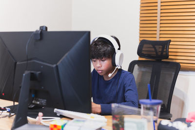 Teenage boy doing homework on computer at home.