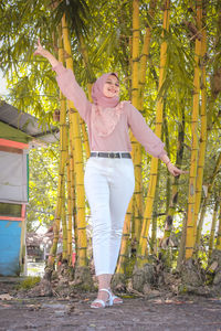 Portrait of young woman standing by plants