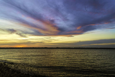 Scenic view of sea against dramatic sky during sunset