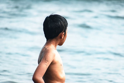 Shirtless boy standing at beach