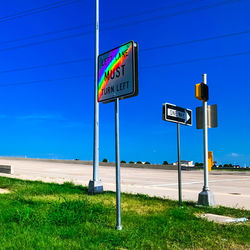 Road sign on field against sky