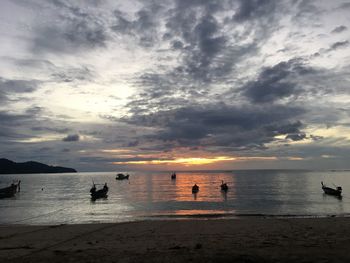 Silhouette people on beach against sky during sunset