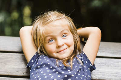 Portrait of cute smiling girl sitting on bench
