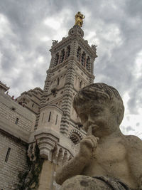 Low angle view of statue of historic building against cloudy sky