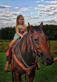 Portrait of smiling girl standing on field against sky