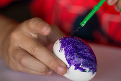 Midsection of child coloring easter egg