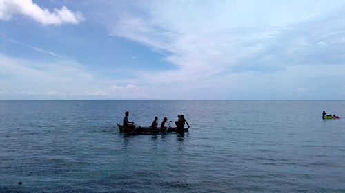 People in sea against sky