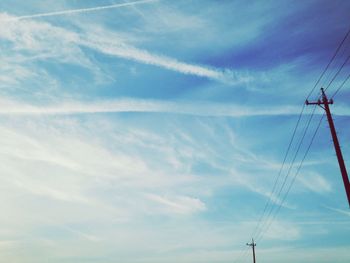 Low angle view of electricity pylon against cloudy sky