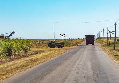 Road amidst field against clear sky