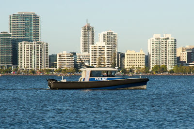 Boat in river with city in background