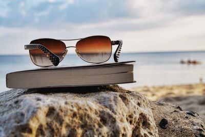 Sunglasses on rocks by sea against sky