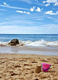 Deck chairs on beach against sky