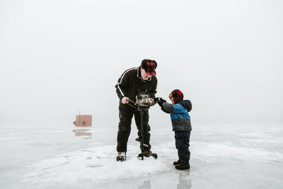 Boy standing on snow covered landscape during winter