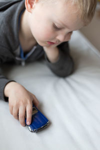 High angle view of boy playing with toy car on bed