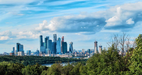 Moscow city daytime panorama with green trees and river under blue cloudy sky