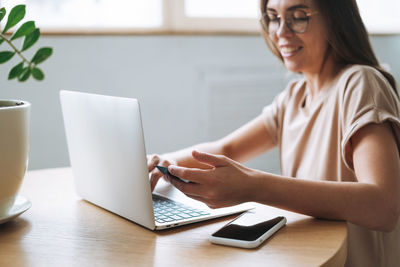 Midsection of woman using mobile phone at table