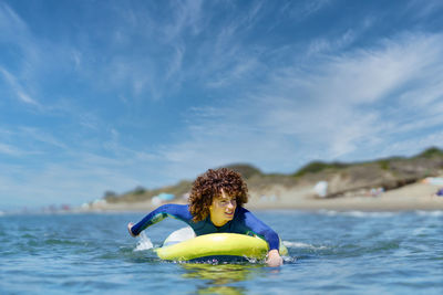 Young woman swimming in sea against sky