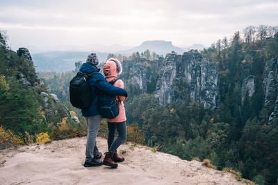 Full length of couple standing on mountain against sky