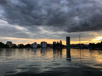 River by buildings against sky during sunset