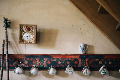 Clock and cups hanging on wall at home