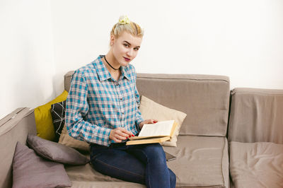 Smiling young woman sitting on sofa at home