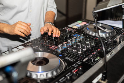 Hands of dj tweak various track controls on dj sound mixer