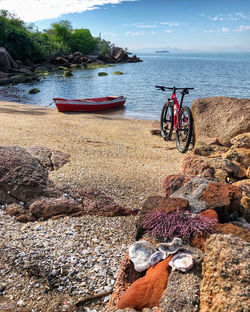 Bicycle on rock by sea against sky