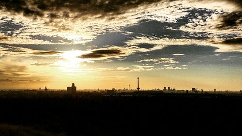 Silhouette of city against cloudy sky