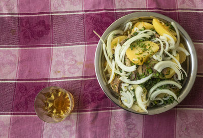 Directly above shot of khashlama in container with oil on tablecloth