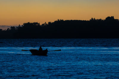 Silhouette of boat in sea at sunset