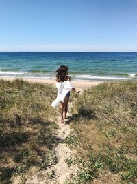 Rear view of woman running towards the sea