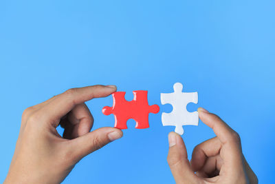Midsection of hand holding toy against blue background