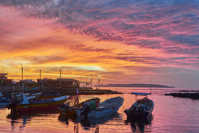 Boats moored at harbor during sunset