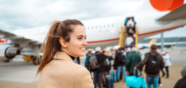 Portrait of young woman standing against sky