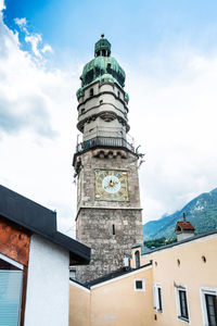 Low angle view of clock tower in city against cloudy sky