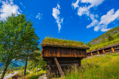 Low angle view of building and trees against blue sky