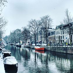 Boats moored on river in city against sky