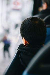 Rear view of boy sitting by window in bus