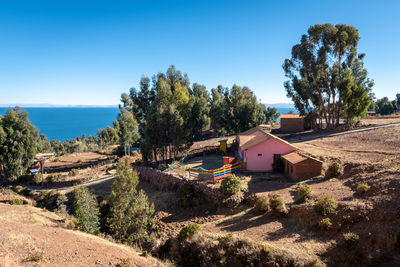 Panoramic view of trees and houses against clear blue sky