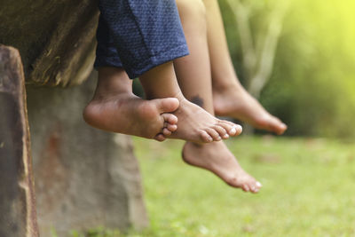 Low section of children sitting on bench at park