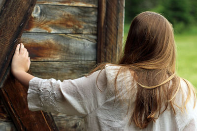 Rear view of woman standing by wooden wall at farm