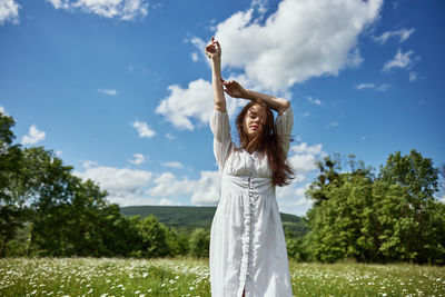 Rear view of woman standing on field against sky